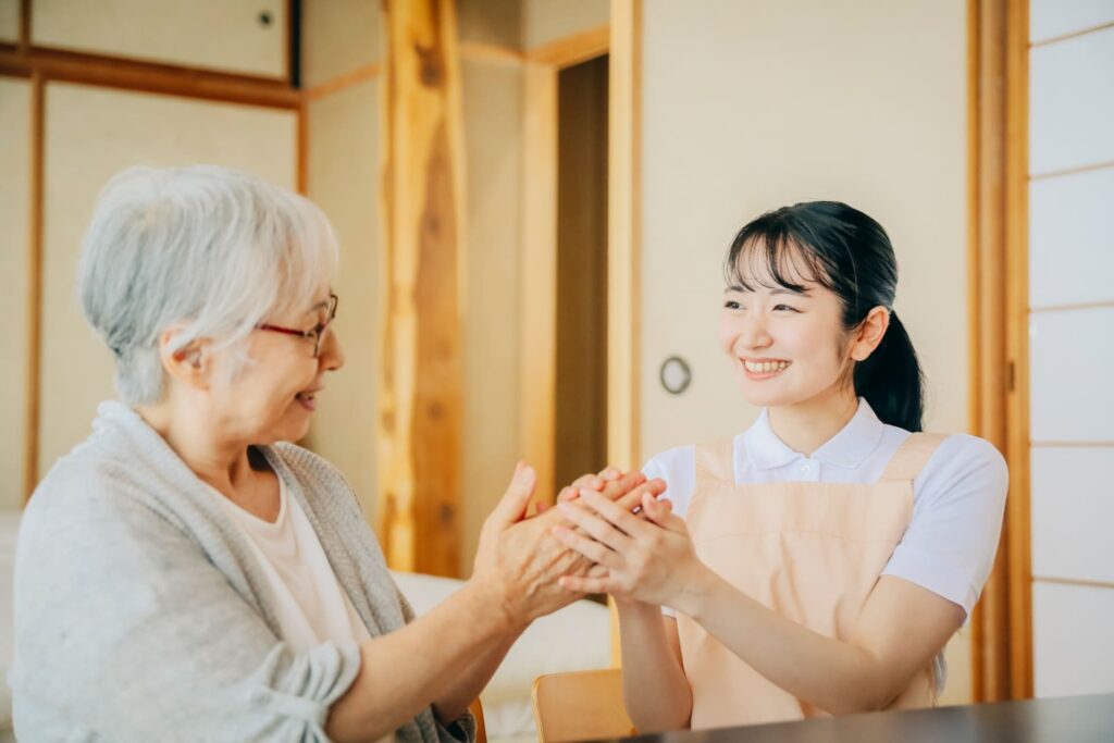 訪問看護員と高齢者が手を握る